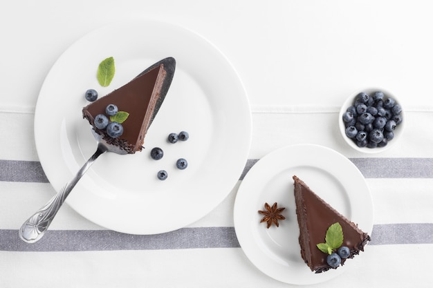 Postura plana de fatias de bolo de chocolate em pratos com mirtilos