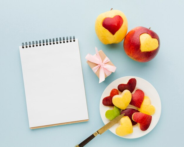 Postura plana de formas de coração de frutas com notebook e presente