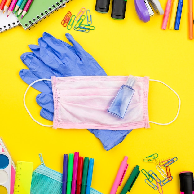 Postura plana de itens essenciais da escola com luvas e máscara médica