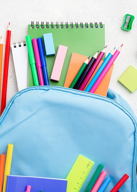 Postura plana de itens essenciais da escola com mochila e lápis