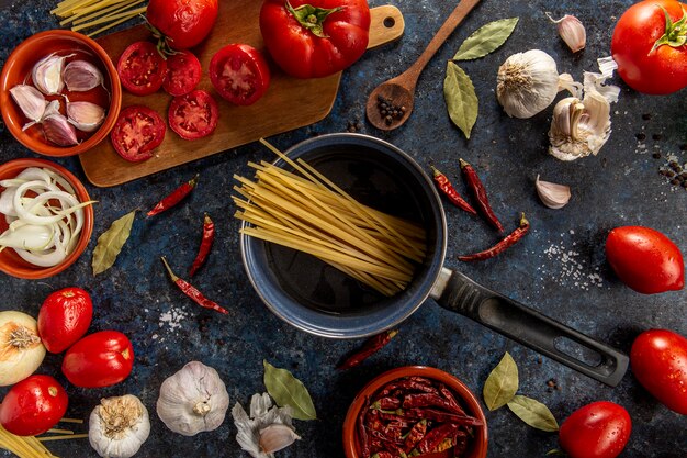 Postura plana de macarrão na panela com tomates e legumes