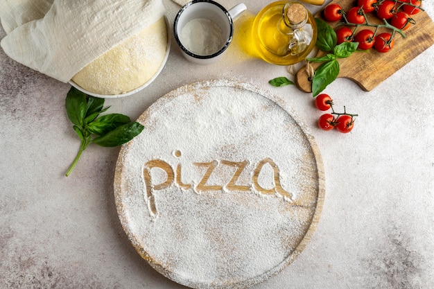Postura plana de massa de pizza com placa de madeira e palavra escrita em farinha