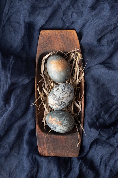 Foto grátis postura plana de ovos de páscoa na placa de madeira e têxteis