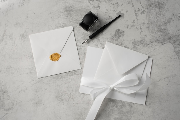 Postura plana de papel de casamento e envelope com tinta e caneta
