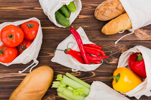 Foto grátis postura plana de sacos reutilizáveis na superfície de madeira com frutas e legumes