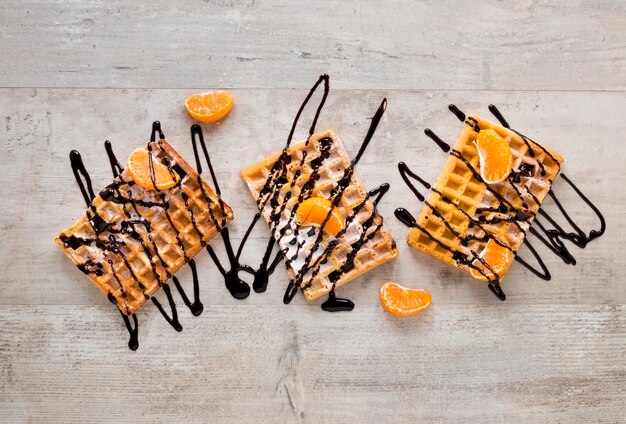 Postura plana de waffles cobertos com calda de chocolate e tangerinas