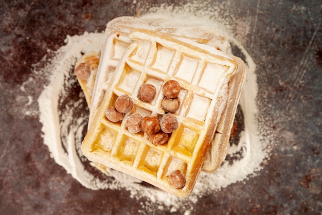 Foto grátis postura plana de waffles com avelãs e açúcar em pó