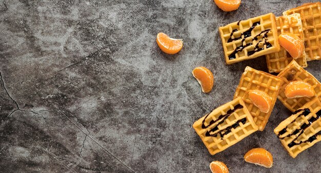 Postura plana de waffles com calda de chocolate e tangerinas