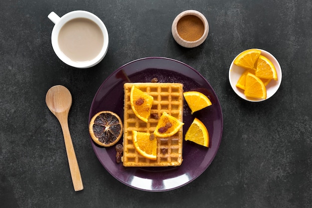 Postura plana de waffles no prato com frutas cítricas e café