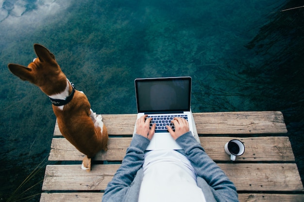 Pov de um homem tomando café e trabalhando no laptop no lago