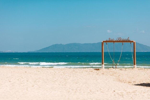 Praia de areia com arco de madeira decorativo perto do mar