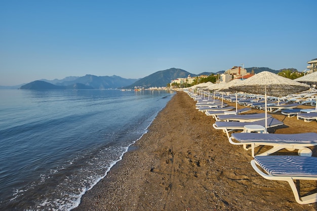 Praia de areia sem pessoas e com espreguiçadeiras guarda-sóis palmeiras Marmaris