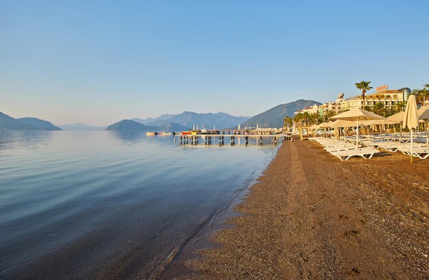 Praia deserta ao sol da manhã A praia ao amanhecer Espreguiçadeiras vazias Praia sem pessoas Marmaris