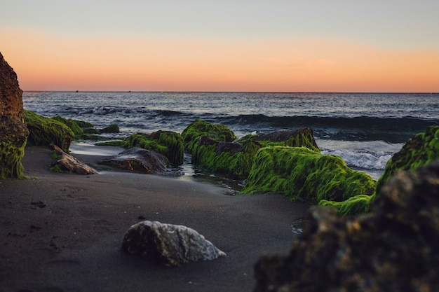 Praia rochosa ao pôr do sol