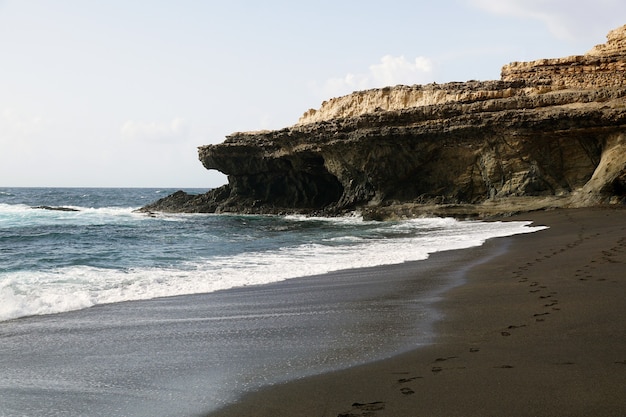 Praia rodeada por rochas e pelo mar sob o sol nas Ilhas Canárias