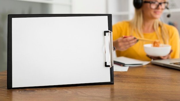 Foto grátis prancheta de close-up na mesa com uma mulher atrás