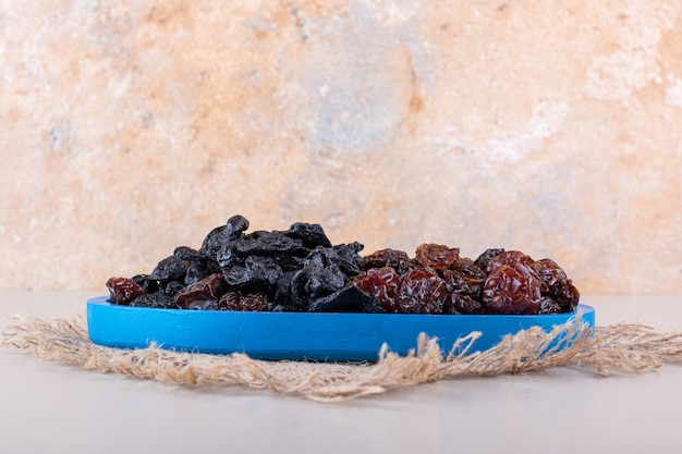 Prato azul cheio de saborosas ameixas secas em fundo branco. foto de alta qualidade