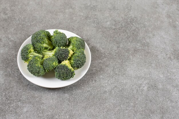 Prato branco de brócolis fresco saudável na mesa de pedra.