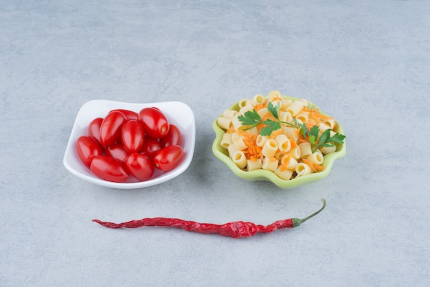 Foto grátis prato branco de tomate cereja e prato verde de delicioso macarrão