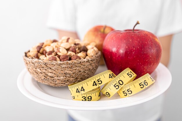 Prato com maçãs nozes e fita métrica dieta e conceito de comida saudável