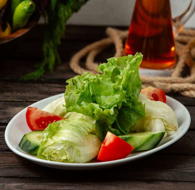 Prato com tomate picado e pepino e alface em cima da mesa