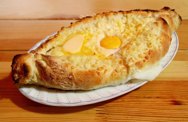 Prato de adjaruli khachapuri, queijo georgiano tradicional e pão de ovo servido na mesa de madeira
