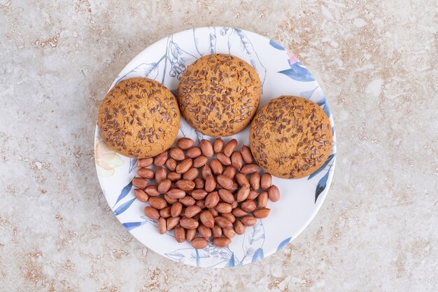 Prato de biscoitos de aveia e grãos de amendoim na superfície de mármore.