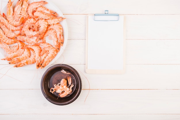 Foto grátis prato de camarão com prancheta na mesa