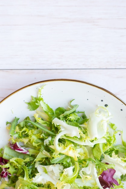 Prato de cerâmica branca com salada fresca na superfície de madeira