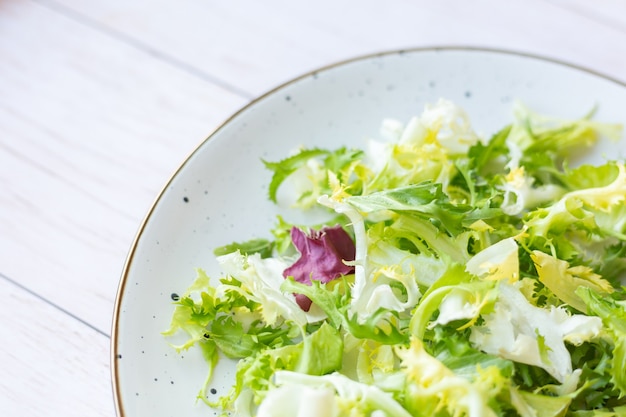 Prato de cerâmica branca com salada fresca na superfície de madeira