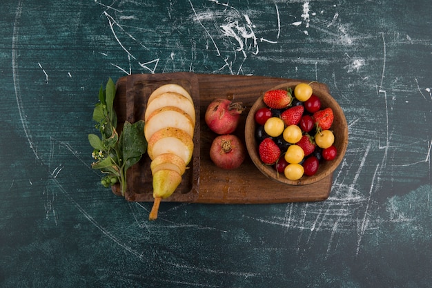 Prato de cereja com romã e peras em uma travessa de madeira no meio