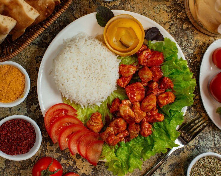 Foto grátis prato de frango com pedaços de frango em molho de tomate, servido com arroz e tomate