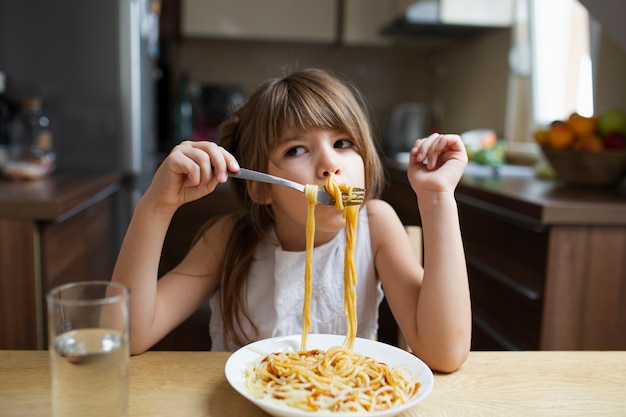 Foto grátis prato de macarrão servido a menina brincalhão