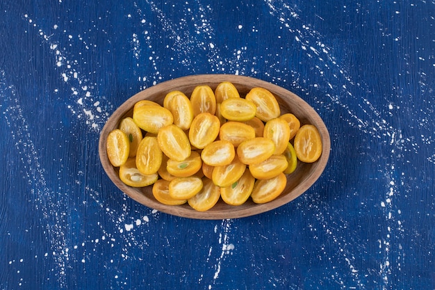 Foto grátis prato de madeira com frutas fatiadas de kumquat na superfície de mármore