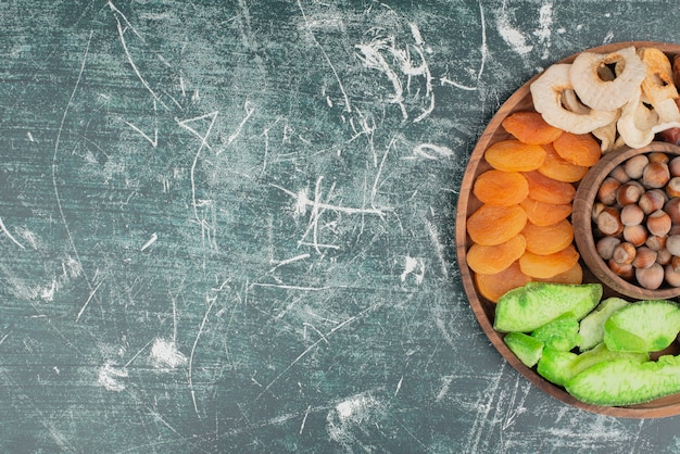 Foto grátis prato de madeira com frutos secos em fundo de mármore