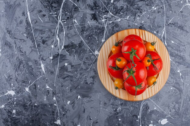 Prato de madeira com tomate cereja e vermelho na superfície de mármore