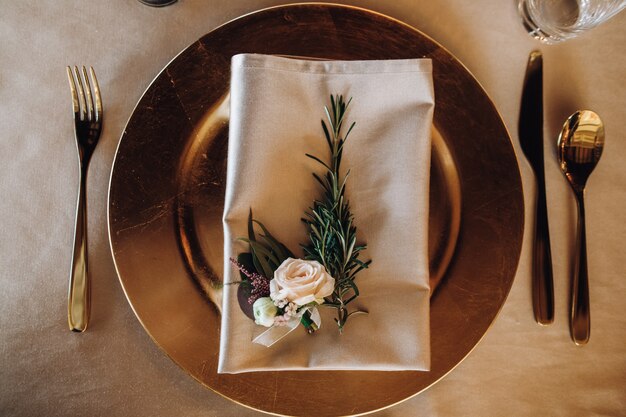 Prato de mesa servindo com folha de pinheiro e rosa em guardanapo