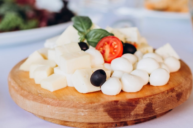 Prato de queijo com um cacho de uvas, mel e nozes. gouda, parmesão, mussarela, gorgonzola em uma placa de madeira.