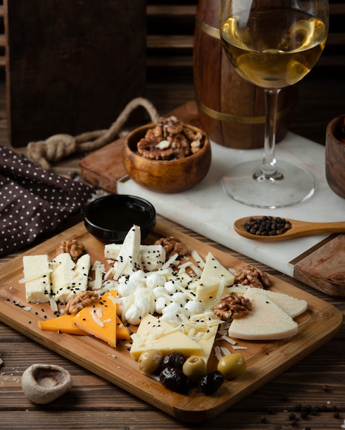 prato de queijo na tábua de madeira com vinho branco