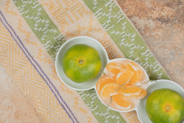 Prato de tangerinas frescas e segmentos na toalha de mesa.