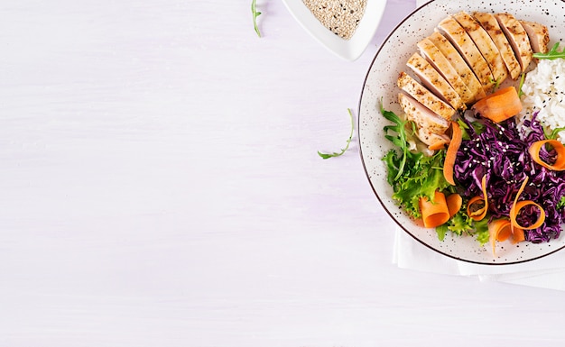Foto grátis prato de tigela de buda com filé de frango, arroz, repolho roxo, cenoura, salada de alface fresca e gergelim.
