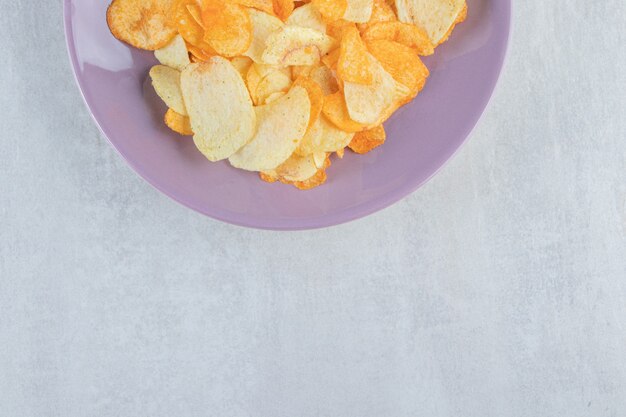 Prato roxo de várias batatas fritas crocantes na pedra.