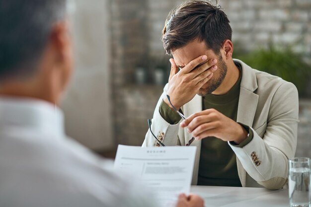 Preocupado candidato masculino tendo uma entrevista de emprego com um gerente no escritório