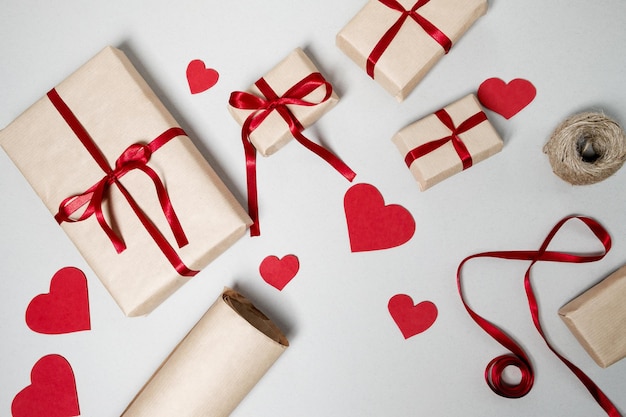 Preparação para o dia dos namorados com fita vermelha de caixas de presente e corações em fundo branco vista superior plana