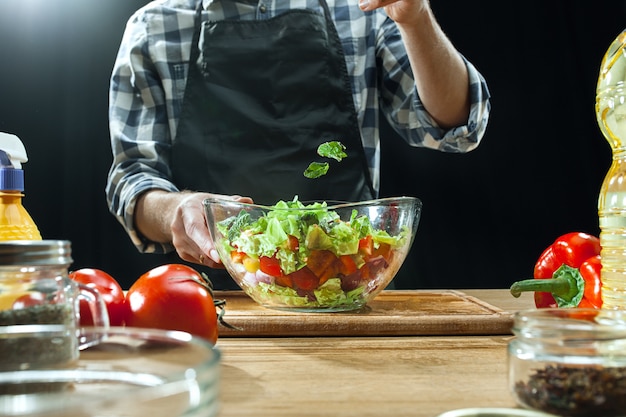 Preparando salada. chef feminino corte de legumes frescos. processo de cozimento. foco seletivo