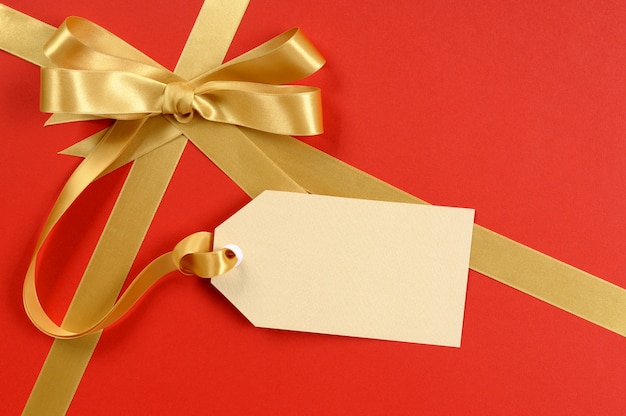 Presente vermelho, laço de fita de ouro, tag presente em branco ou etiqueta, copie o espaço