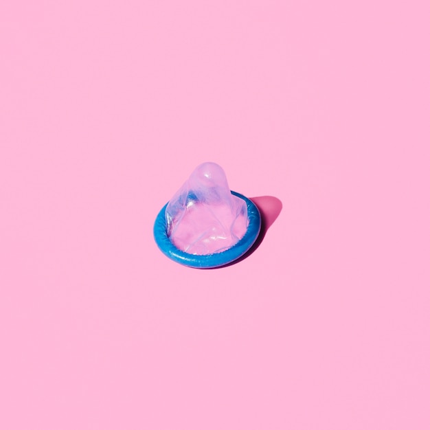 Preservativo azul de alto ângulo em fundo rosa