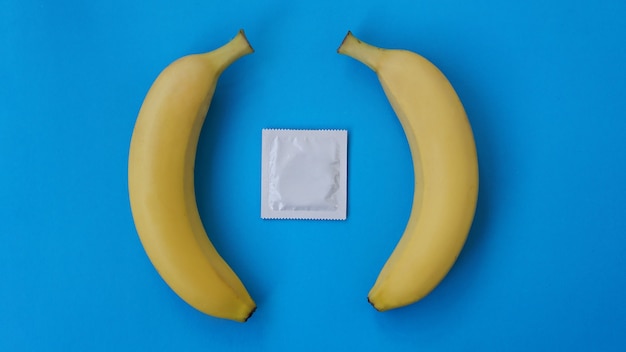 Preservativos e duas bananas juntas sobre fundo azul, o conceito de contraceptivos e a prevenção de doenças venéreas do casamento entre pessoas do mesmo sexo.