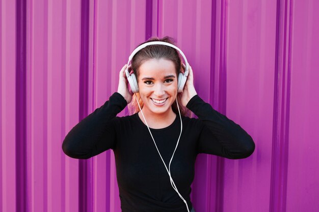 Pretty sportswoman em fones de ouvido sorrindo para a câmera