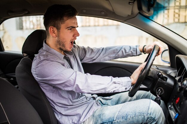 Problemas de tráfego. Bom homem emocional dando um sinal enquanto dirigia um carro